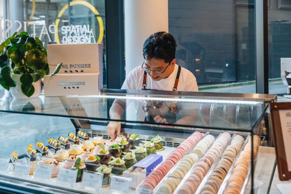 A staff member arranges desserts in the display case at April Patisserie.