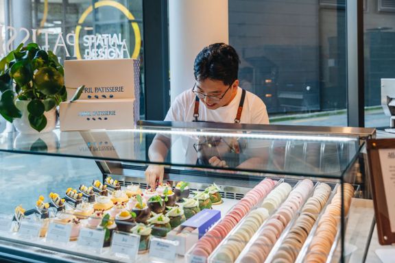 A staff member arranges desserts in the display case at April Patisserie.