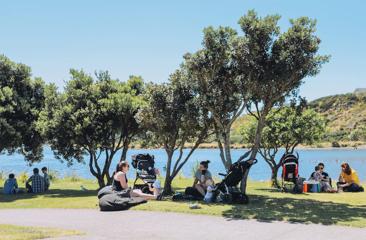 People sitting on the grass outside Get Fixed bicycle Cafe in Porirua under the trees.