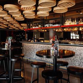 Interior of hot sauce, red and gold decorations on the roof and walls, with the bar on the right and tables around the room.