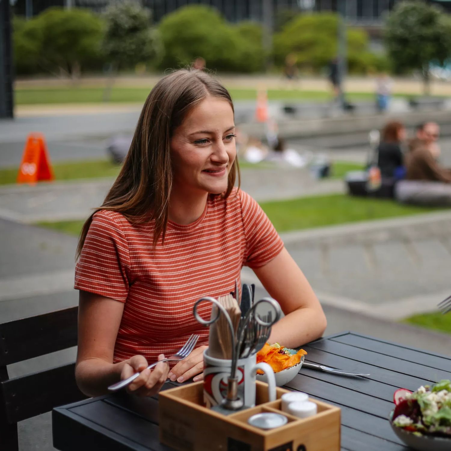 A happy couple eats lunch on the patio at Karaka Café at Te Wharewaka o Pōneke.