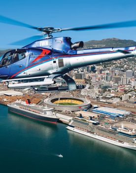 A helicopter flying over the Wellington Harbour with the city centre visible in the background.