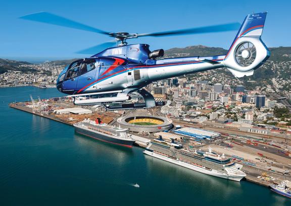 A helicopter flying over the Wellington Harbour with the city centre visible in the background. 