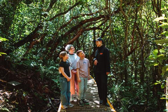 A family of three is on a guided walking tour at Zealandia.