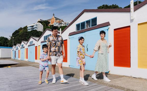 A family walking along the boat sheds at Oriental Bay.