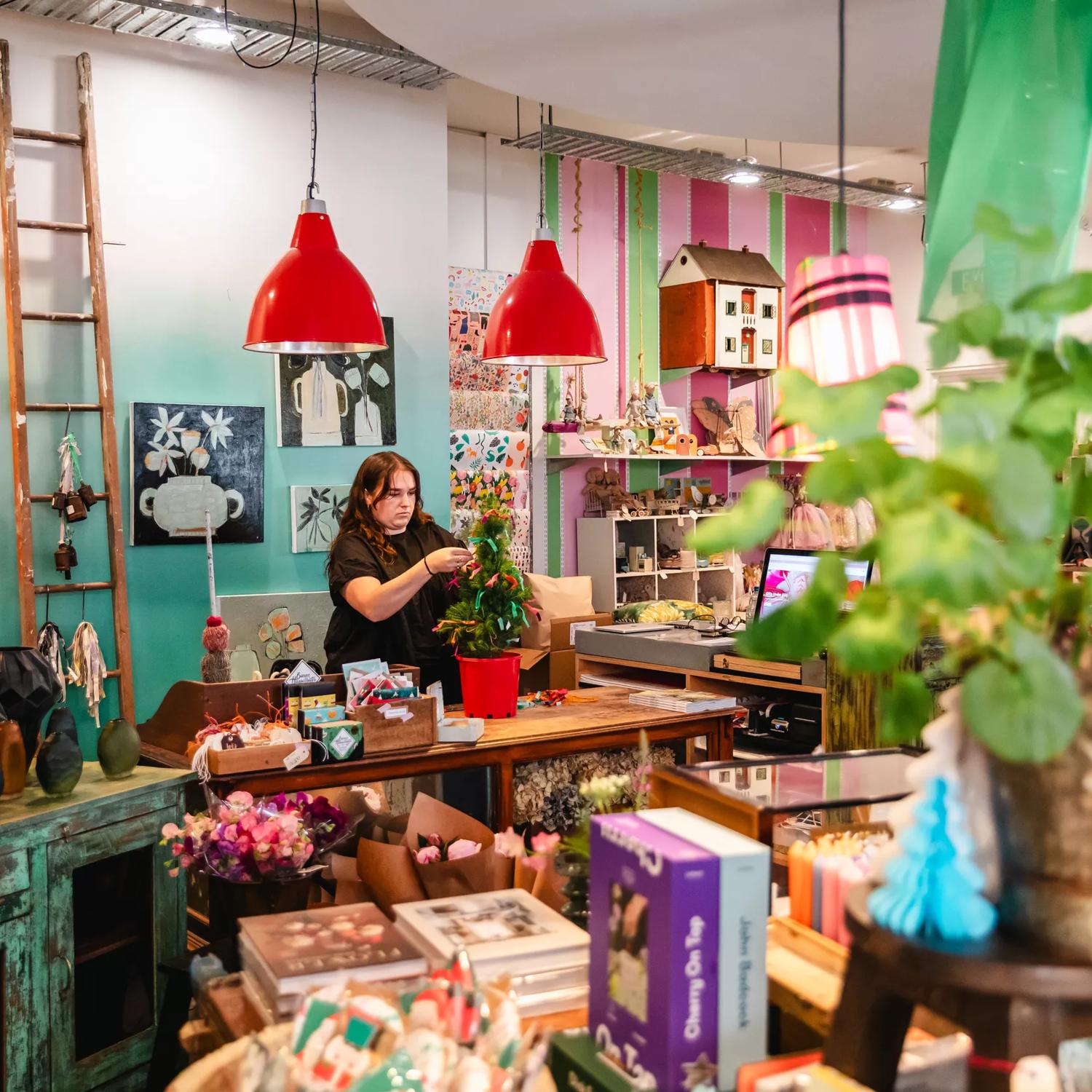 Staff decorating a small christmas tree inside Small Acorns gift shop.