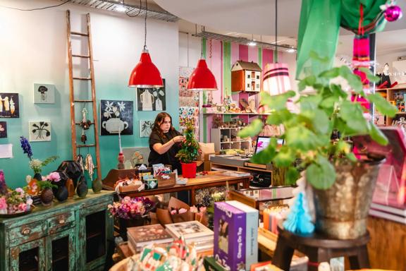 Staff decorating a small christmas tree inside Small Acorns gift shop.