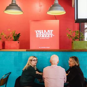 Interior with customers sitting down chatting, light blue and orange painted walls light up the space.