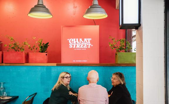 Interior with customers sitting down chatting, light blue and orange painted walls light up the space.