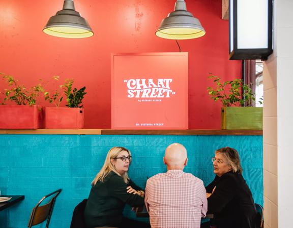 Interior with customers sitting down chatting, light blue and orange painted walls light up the space.