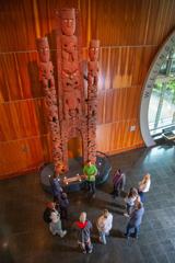 Nine people standing in a circle with a tour guide from Te Papa who is wearing a bright green t-shirt.