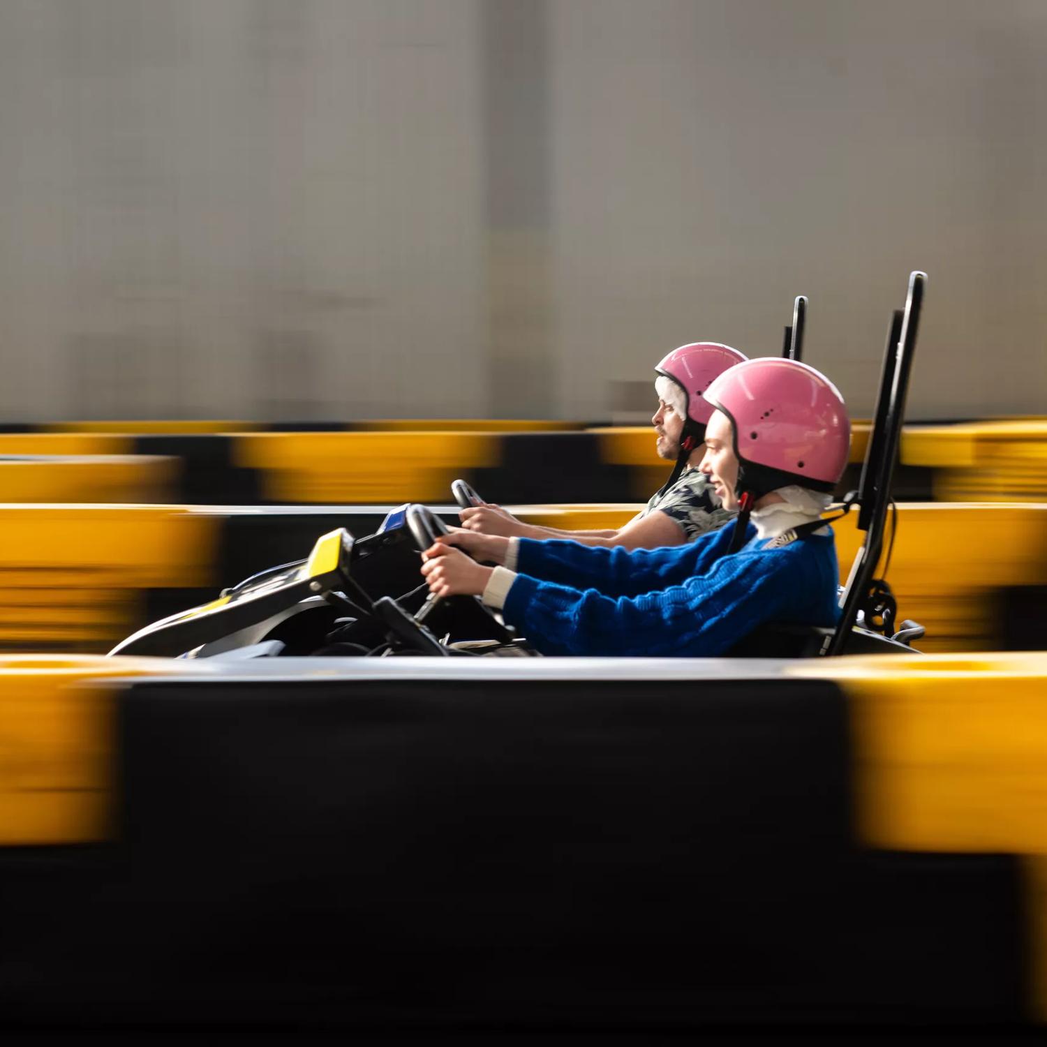 Two people racing in go-karts at Daytona Adventure Park in Upper Hutt. People are in focus whilst the rest of the image is blurred to show speed.
