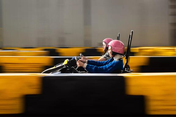 Two people racing in go-karts at Daytona Adventure Park in Upper Hutt. People are in focus whilst the rest of the image is blurred to show speed.