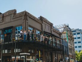 People enjoy the sunshine and drinks on the Balcony at Regent.