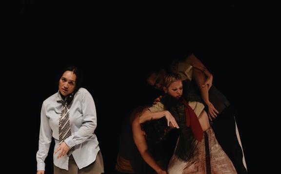 Three dancers perform Mysthomia on a dark stage.