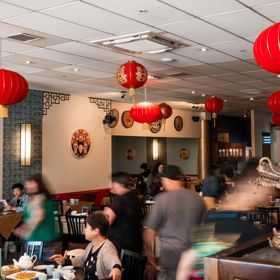 Inside a busy Chinese restaurant with red lanterns suspended from the ceiling.