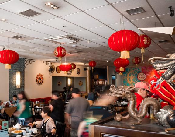 Inside a busy Chinese restaurant with red lanterns suspended from the ceiling.