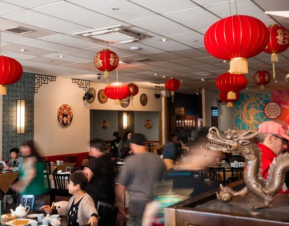 Inside a busy Chinese restaurant with red lanterns suspended from the ceiling.