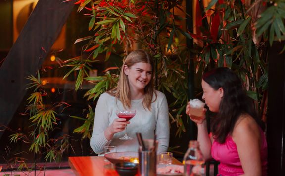 Two people drinking from cocktails in Dragonfly, a bar on Courtenay Place.