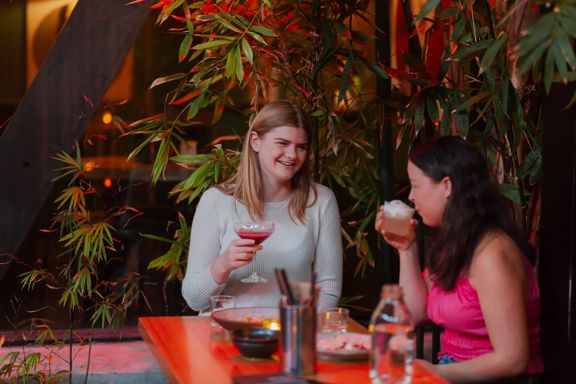 Two people drinking from cocktails in Dragonfly, a bar on Courtenay Place.