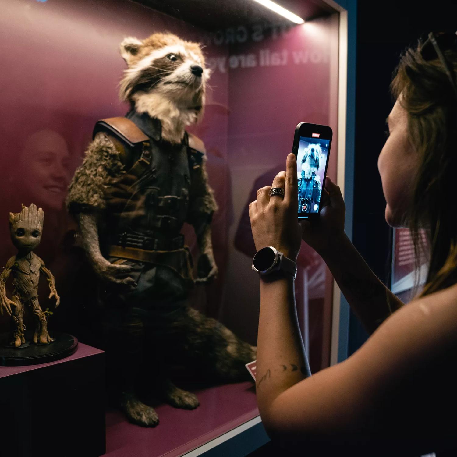 A person taking a picture of the Rocket Racoon and Groot from the Guardians of the Galaxy franchise at Marvel: Earth's Mightiest Exhibition at Tākina.