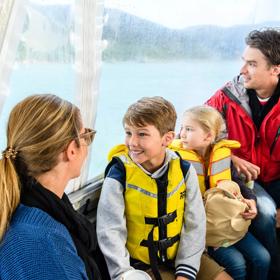 Two adults and two children are seated on a boat on Kapiti Island Nature Tours.