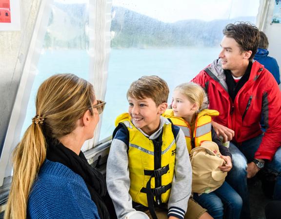 Two adults and two children are seated on a boat on Kapiti Island Nature Tours.