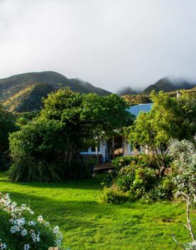 The screen location of Ōrongorongo Station, with many buildings, old and new, as well as views of the ocean and mountains.