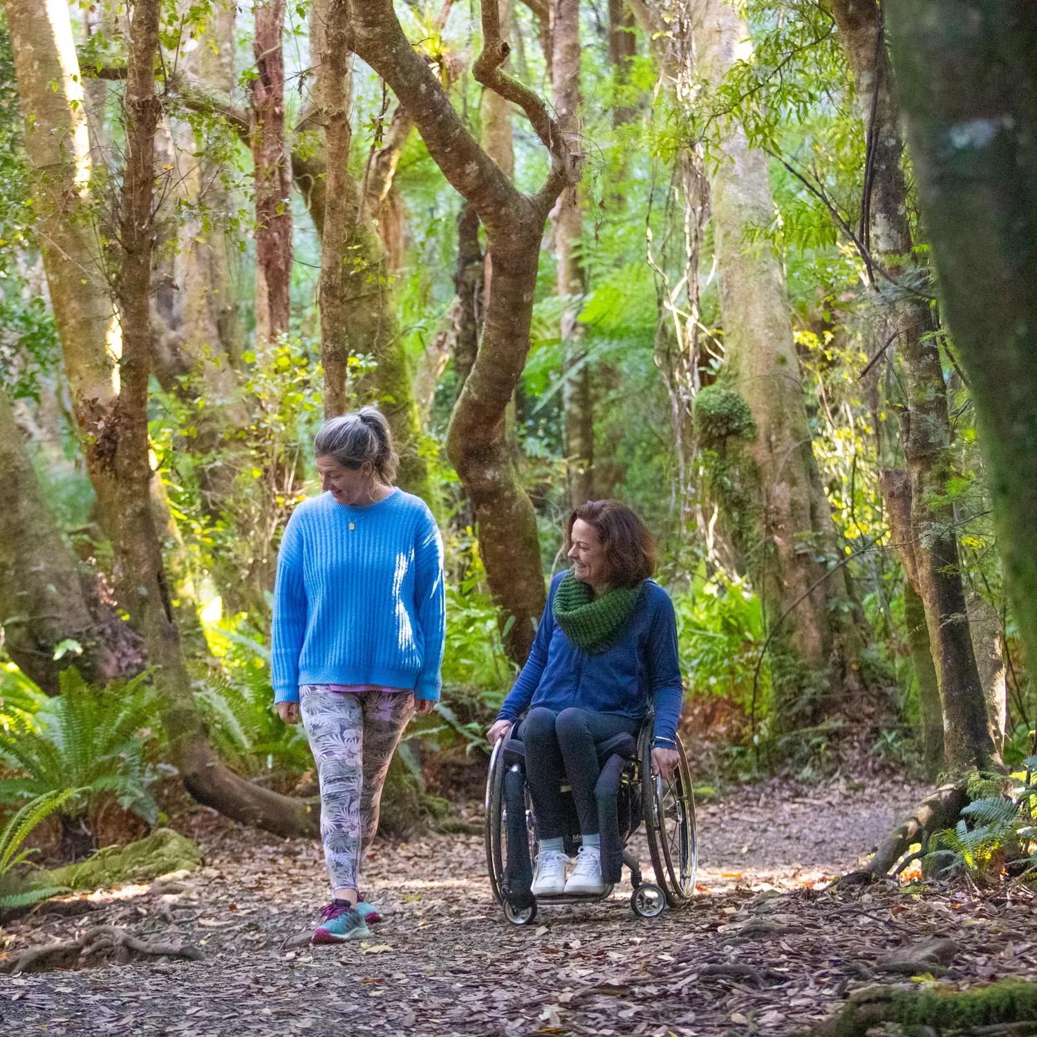 Two people are on a nature trail, one is a wheelchair user. 
