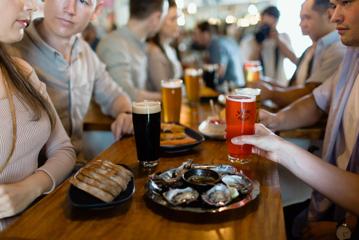 People sit at a table at the Garage Project Taproom with a plate of bread and oysters.