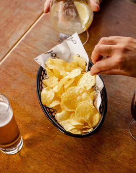 A hand picking up a potato chip from a basket on a table at Ascot, a wine and cocktail bar in Te Aro, Wellington.