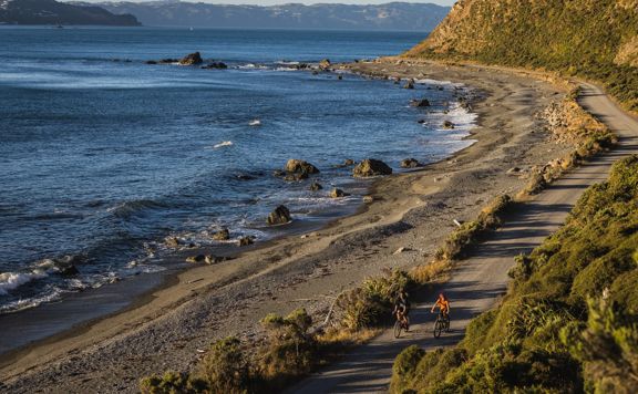 2 bikers on Pencarrow Coast Road, with the Wellington Harbour in the background.