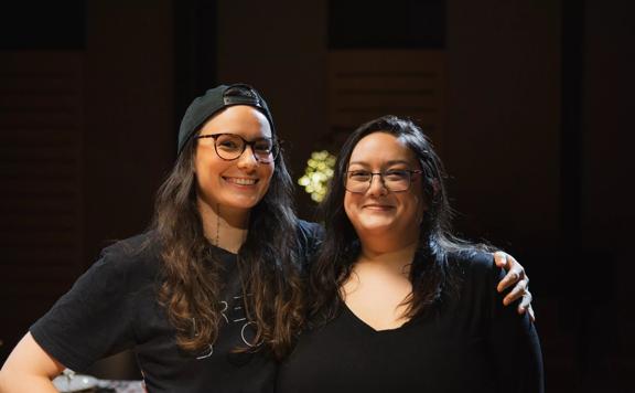 Casey Zilbert  and Pachali Brewster smile for the camera against a black backdrop.