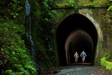 Two bikers going through a dark tunnel on the Rail Trail Section on the Remutaka Cycle Trail.