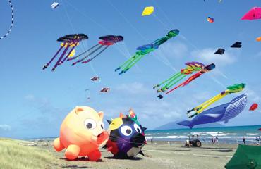 Colourful and quirky kits flying in the blue sky on a beach.