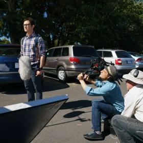 Filming of the TV show Mr. Corman. Joseph Gordon-Levitt stands in a car park with film crew crouched around him.