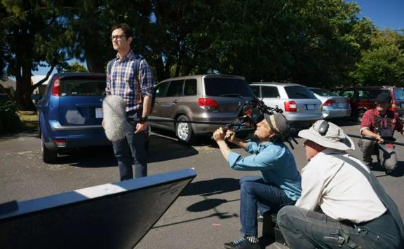 Filming of the TV show Mr. Corman. Joseph Gordon-Levitt stands in a car park with film crew crouched around him.