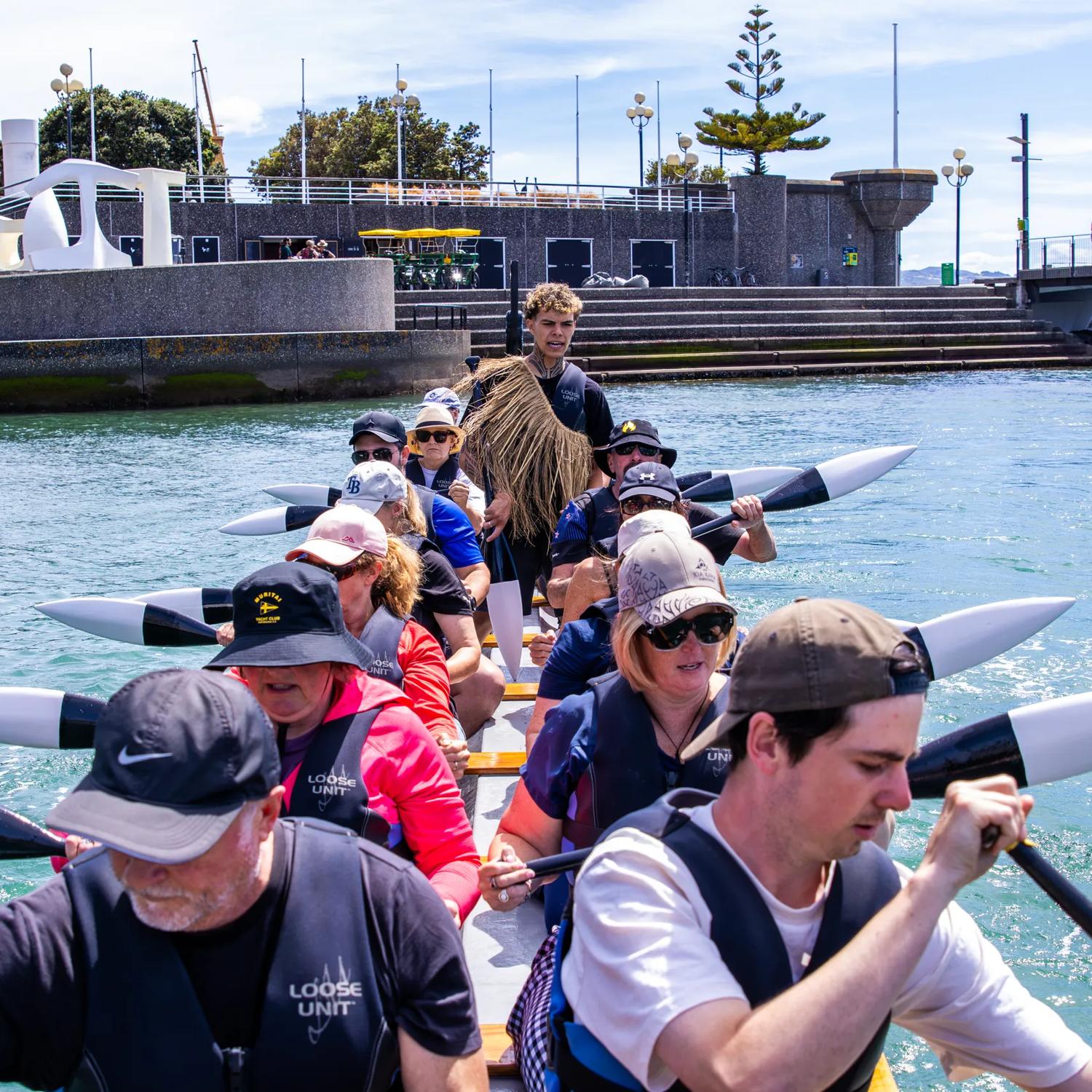 A group of people paddle a waka in Whairepo Lagoon in Wellington.