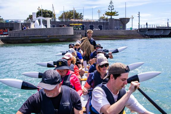 A group of people paddle a waka in Whairepo Lagoon in Wellington.