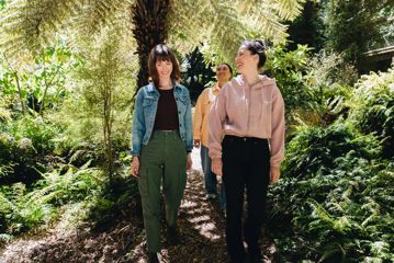 Three friends walk along a forest trail at Ōtari-Wilton's Bush.