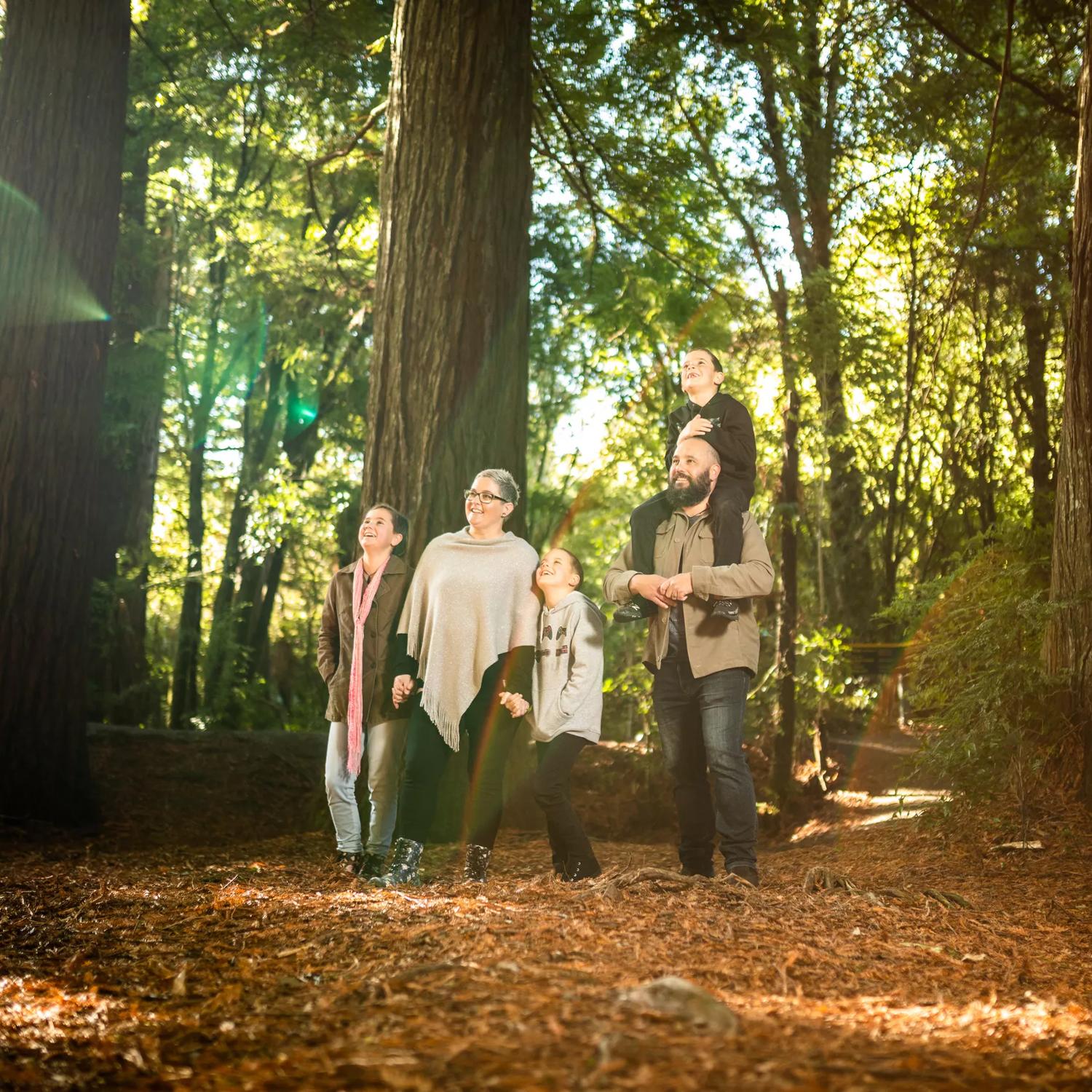 Two adults and three children stand in the middle of the forest, admiring the nature at Pūkaha National Wildlife Centre.