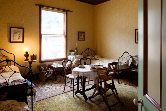 Interior of Katherine Mansfield House in Wellington, featuring a preserved 19th-century bedroom with period furniture, iron beds, and historic décor.