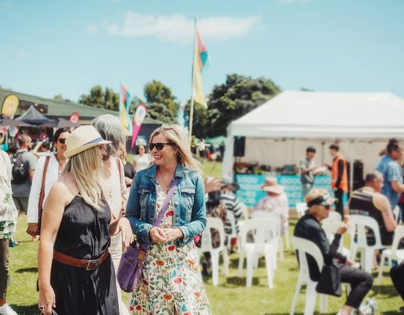 People walking together in the sunshine at the Kāpiti food fair.