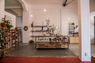 Inside Wellington Apothecary, a health and wellness store. There are white walls, grey tiled floors and tables and shelves with products on display.