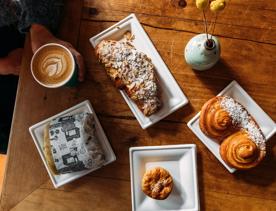 Sweet treats, Pastries, and coffees on a table inside Olde Beach Bakery on the Kāpiti coast.