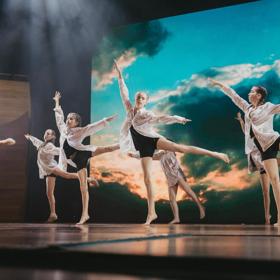 A group of young dancers performing a contemporary piece on stage. 