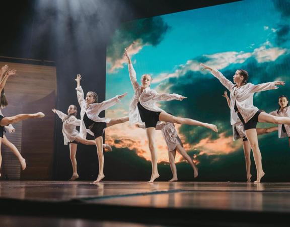 A group of young dancers performing a contemporary piece on stage. 