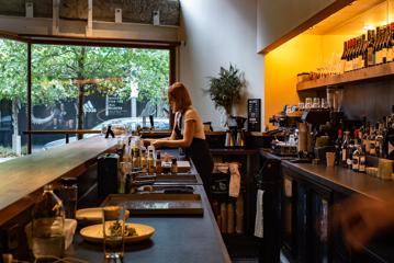 A staff member behind the bar of Highwater eatery serving drinks.