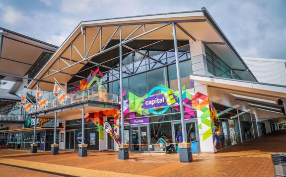 The front of the Capital E building in TSB Arena, with bright colour sign writing along glass windows.