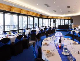 A room inside the Michael Fowler Centre  set up with dining tables for an event overlooking the lagoon on the waterfront.